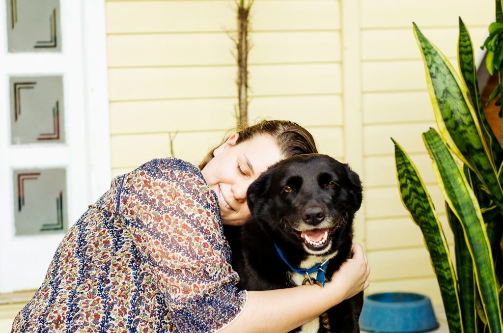 woman hugging black dog