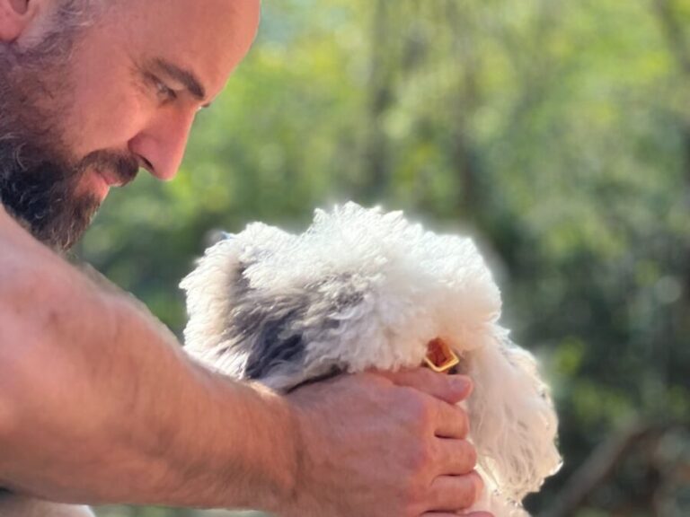 a man is petting a small white dog