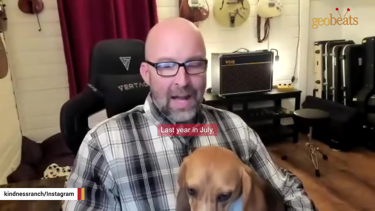 A man with glasses and a plaid shirt holds a beagle puppy while speaking, with a subtitle that reads 'Last year in July,'.