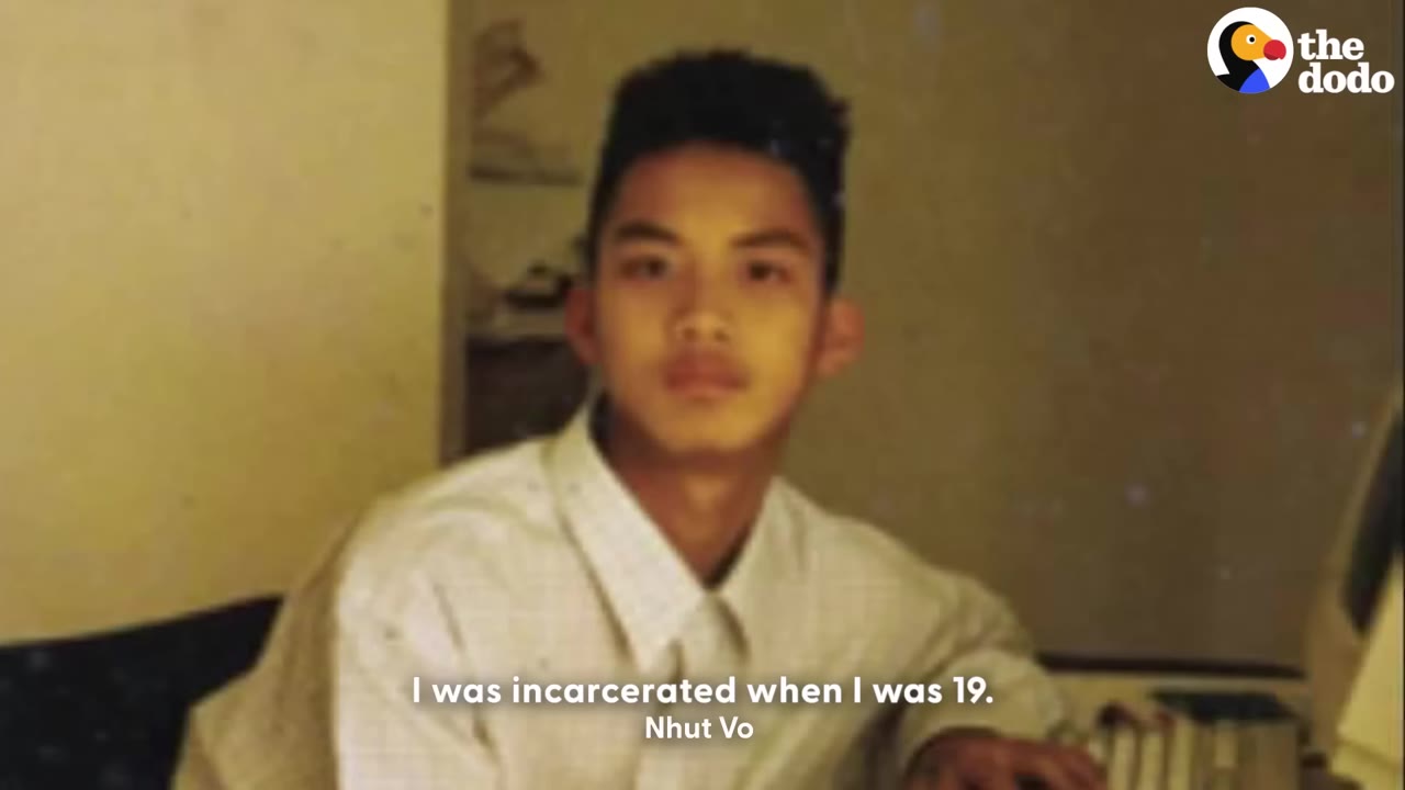 A vintage, slightly blurry photograph of a young man with a high-top haircut wearing a light-colored button-down shirt, looking directly at the camera.