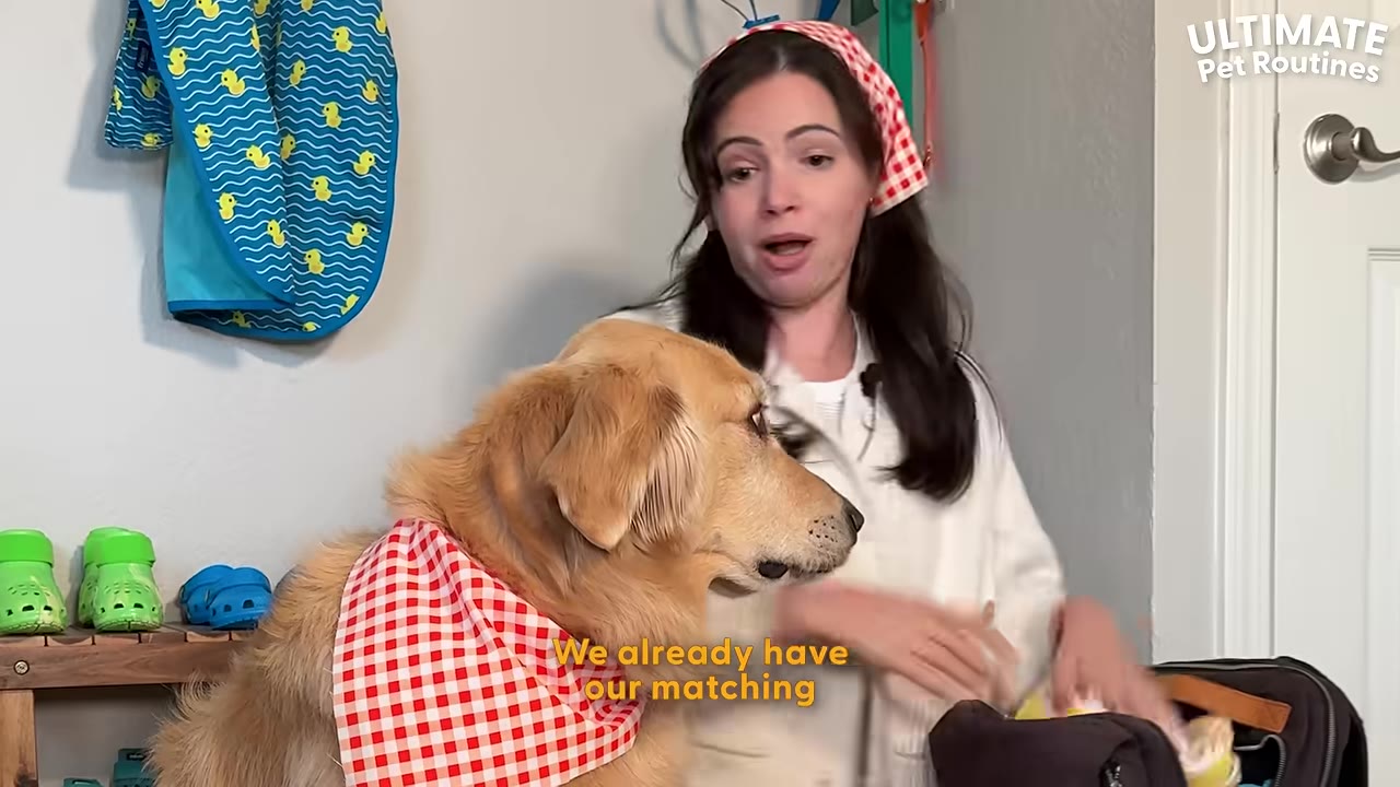A woman wearing a red and white checkered bandana on her head stands next to a golden retriever wearing a matching red and white checkered bandana around its neck.