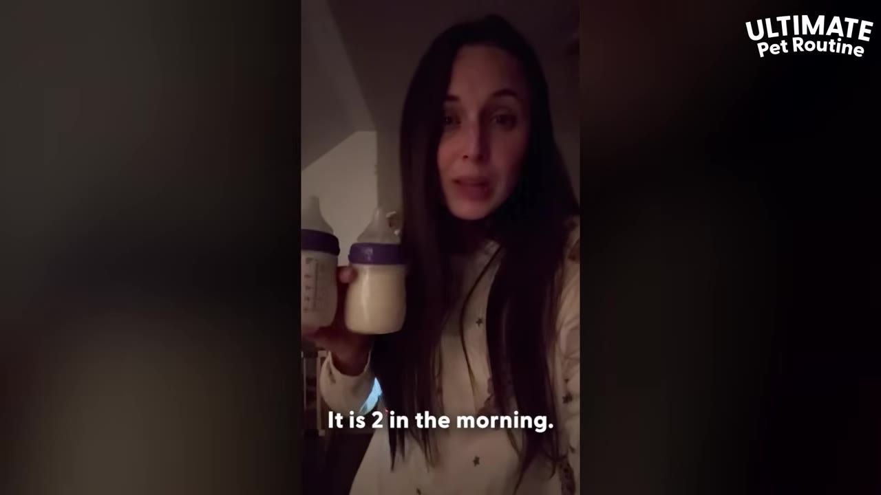 A woman in a dimly lit room holding two baby bottles filled with milk, with text on screen reading 'It is 2 in the morning.'