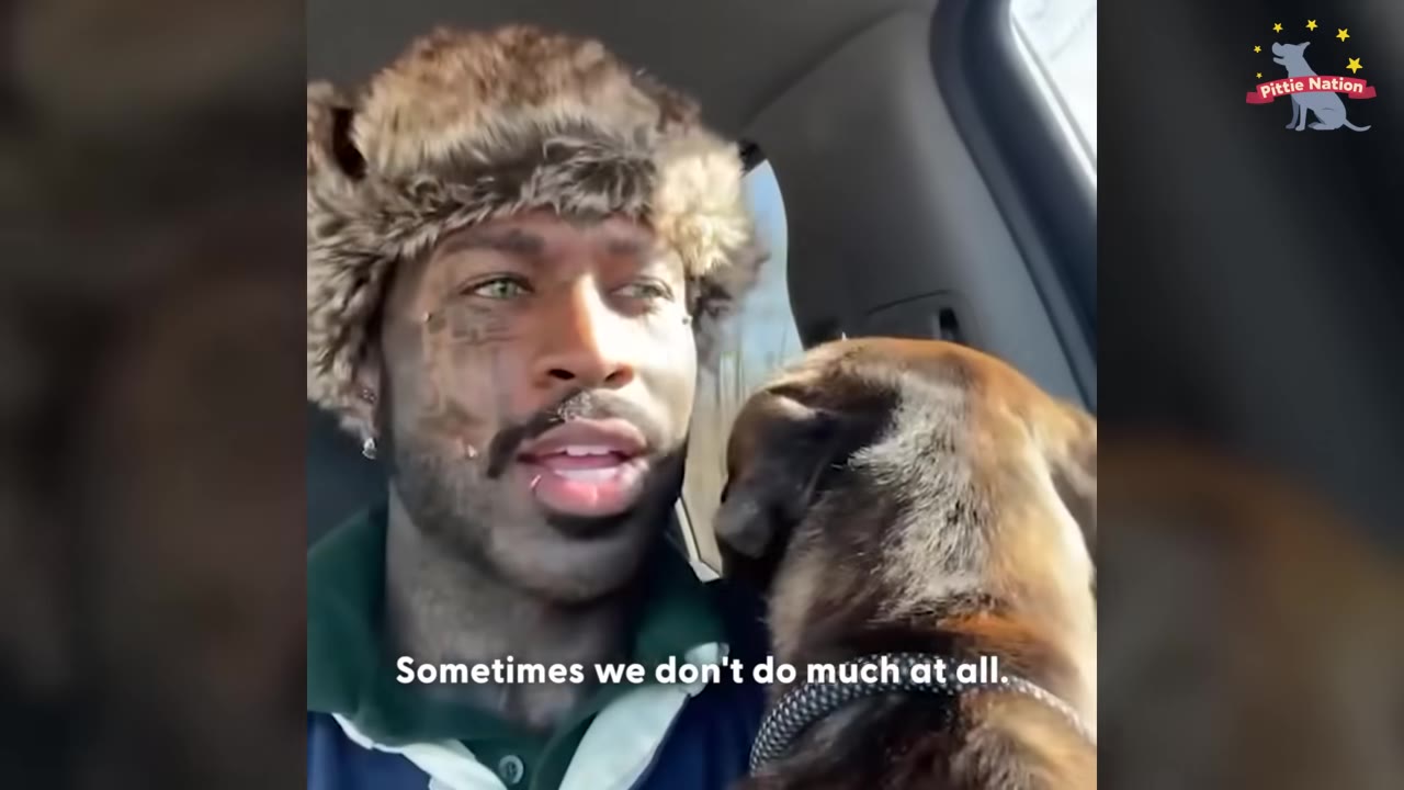 A close-up shot of Yves wearing a furry hat inside a car, looking towards a brown dog sitting next to him, with the subtitle 'Sometimes we don't do much at all.'
