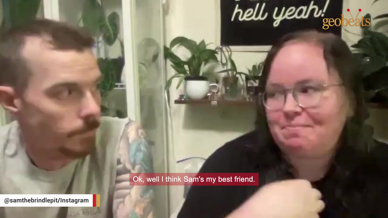 A man with a mustache and a woman with glasses sit side-by-side as she smiles, with a subtitle reading 'Ok, well I think Sam's my best friend.'