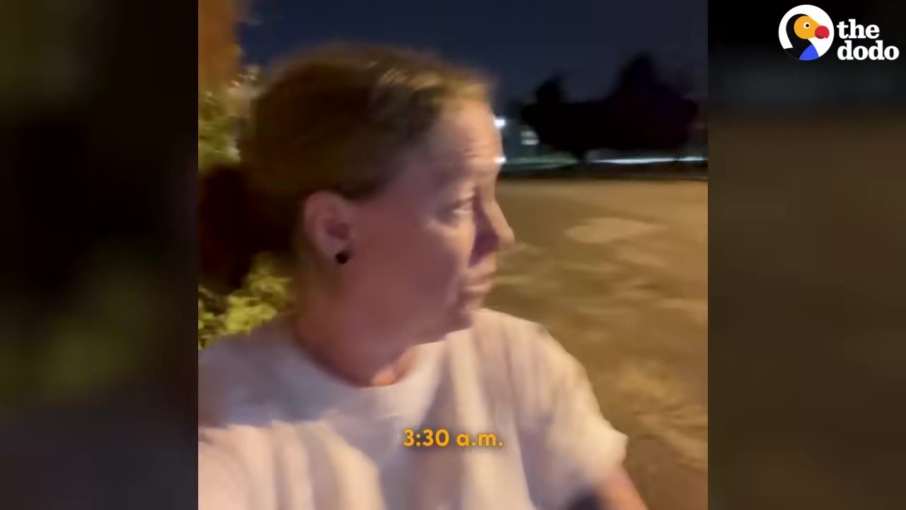 A woman with her hair tied back stands outside at night, looking to the side with a tired expression.