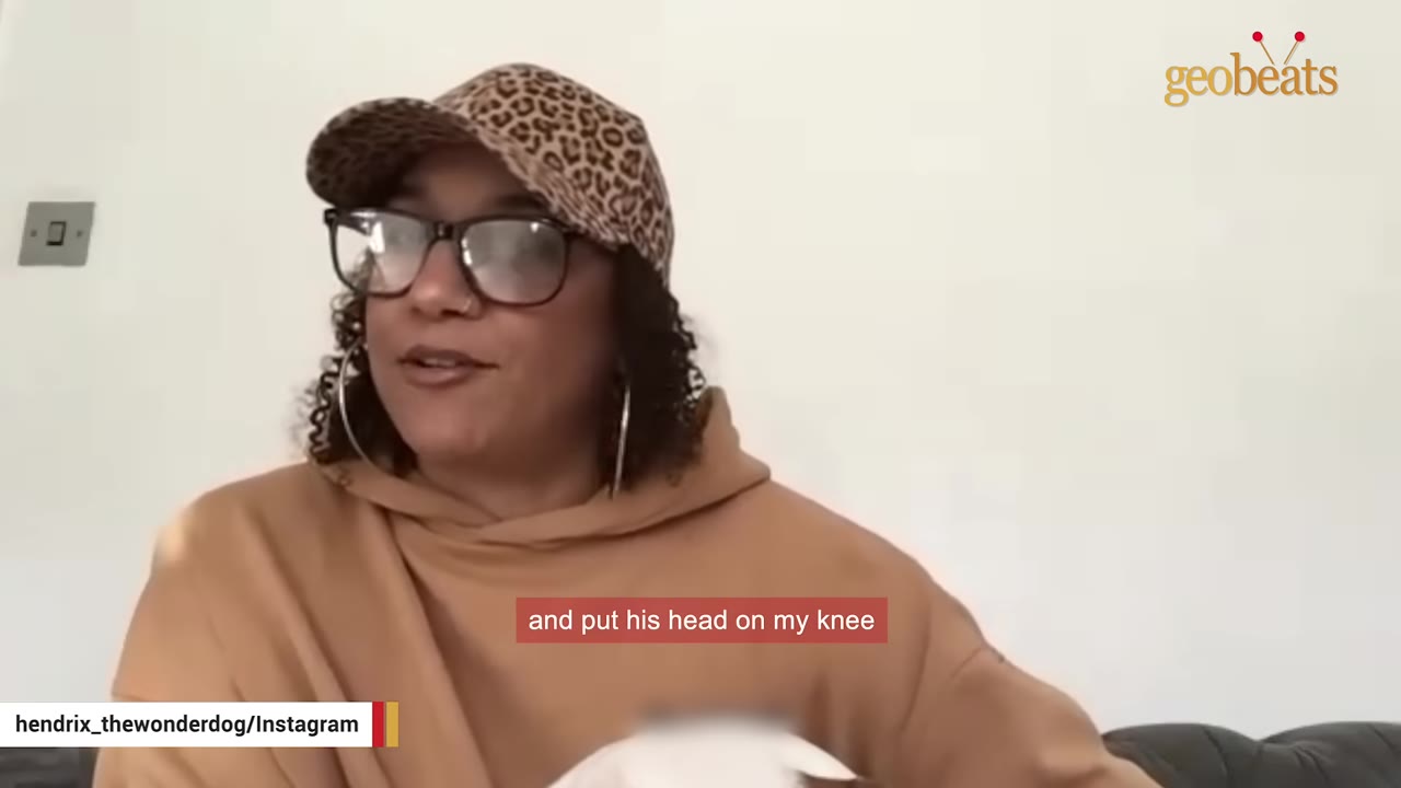 A woman wearing glasses and a leopard-print cap speaks while looking slightly to the side.