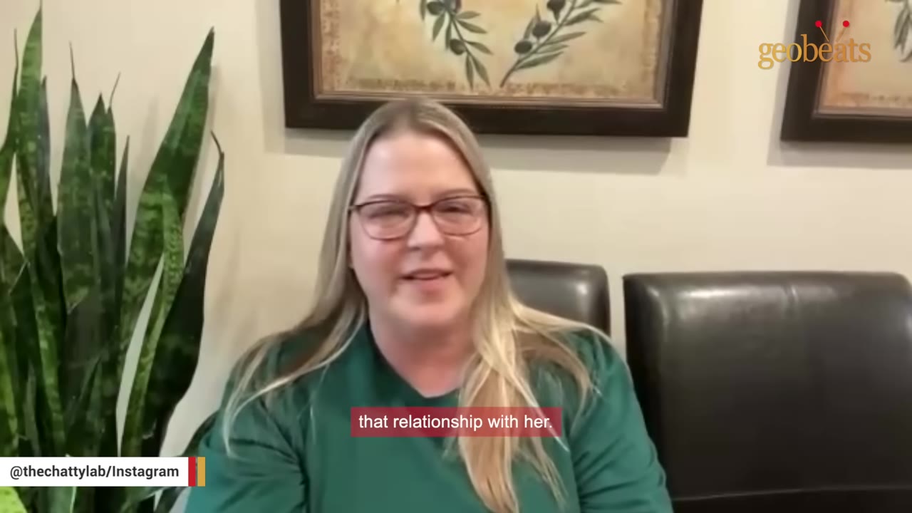 A woman with glasses and blonde hair wearing a green shirt speaks directly to the camera.