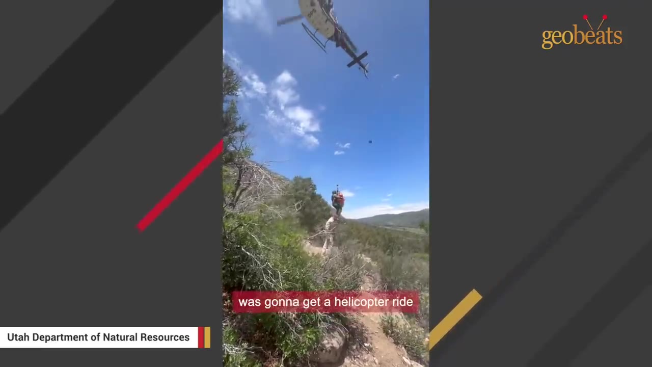 A rescue helicopter hovers above a rugged mountain trail as a person is hoisted up on a line.
