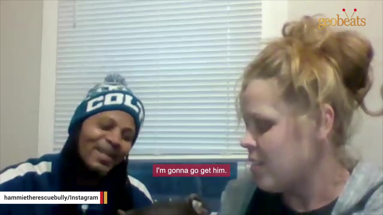 A woman with her hair in a bun and a man wearing a blue beanie talk indoors, with a subtitle reading 'I'm gonna go get him.'