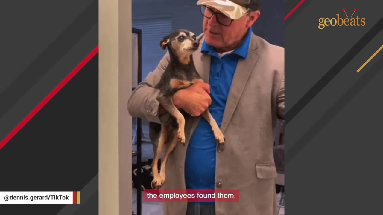 A man wearing glasses, a cap, and a tan blazer holds a small black and tan dog in his arms as they look at each other.