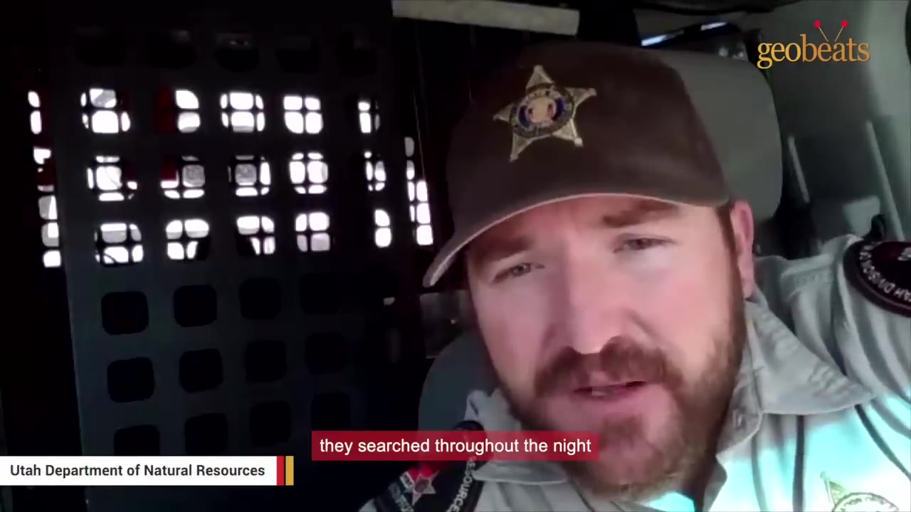 A close-up of a Utah Department of Natural Resources officer in a brown cap with a star badge, speaking inside a vehicle, with the subtitle 'they searched throughout the night' displayed.