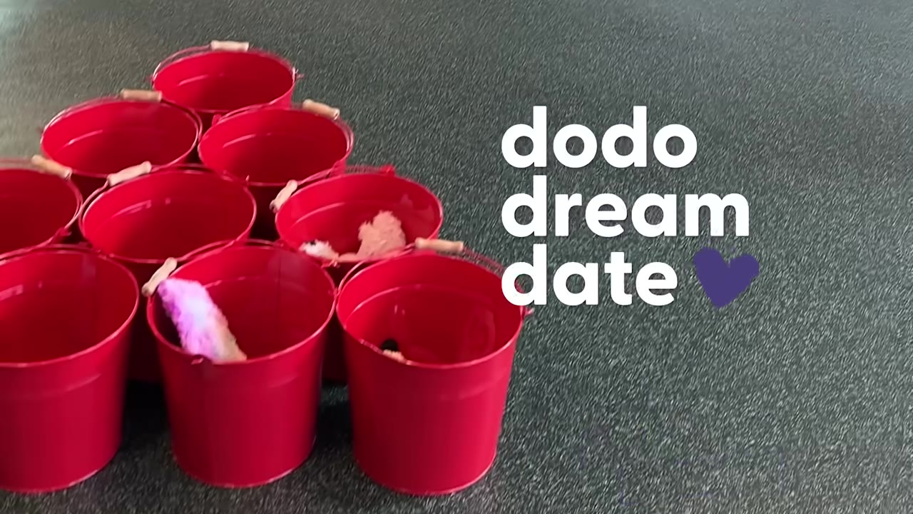 Several red buckets arranged in a triangle on the floor for a game of bucket pong.