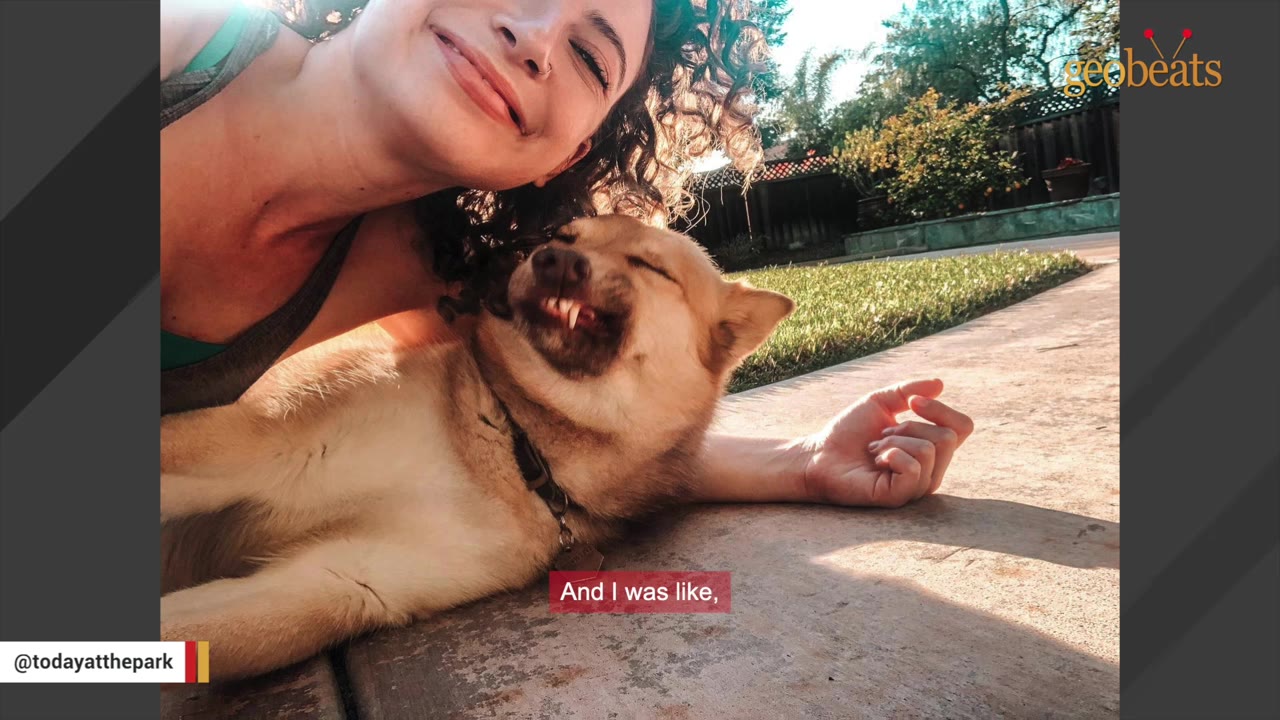 A light brown dog lying on its back on a concrete patio next to a smiling woman, showing a goofy, wide-toothed grin.