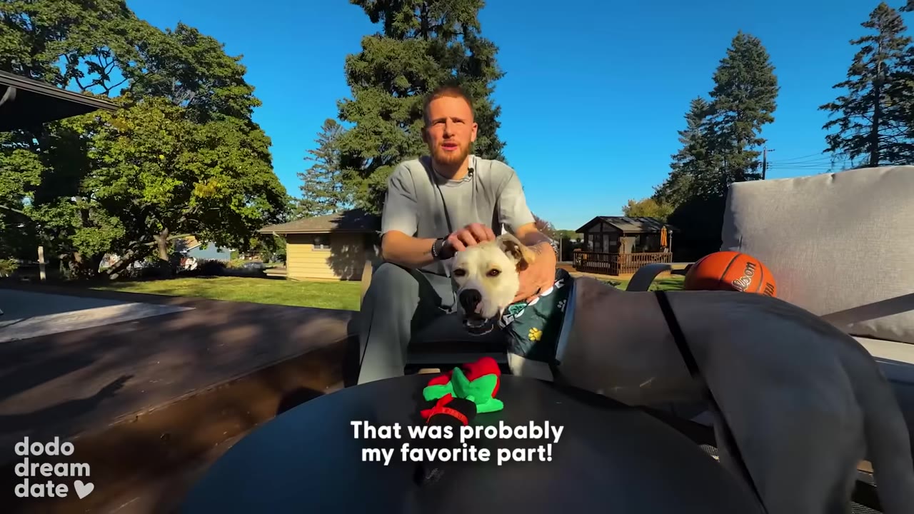 Donte DiVincenzo sits outdoors on a sunny day, petting a white dog wearing a green bandana, with a subtitle that reads 'That was probably my favorite part!'