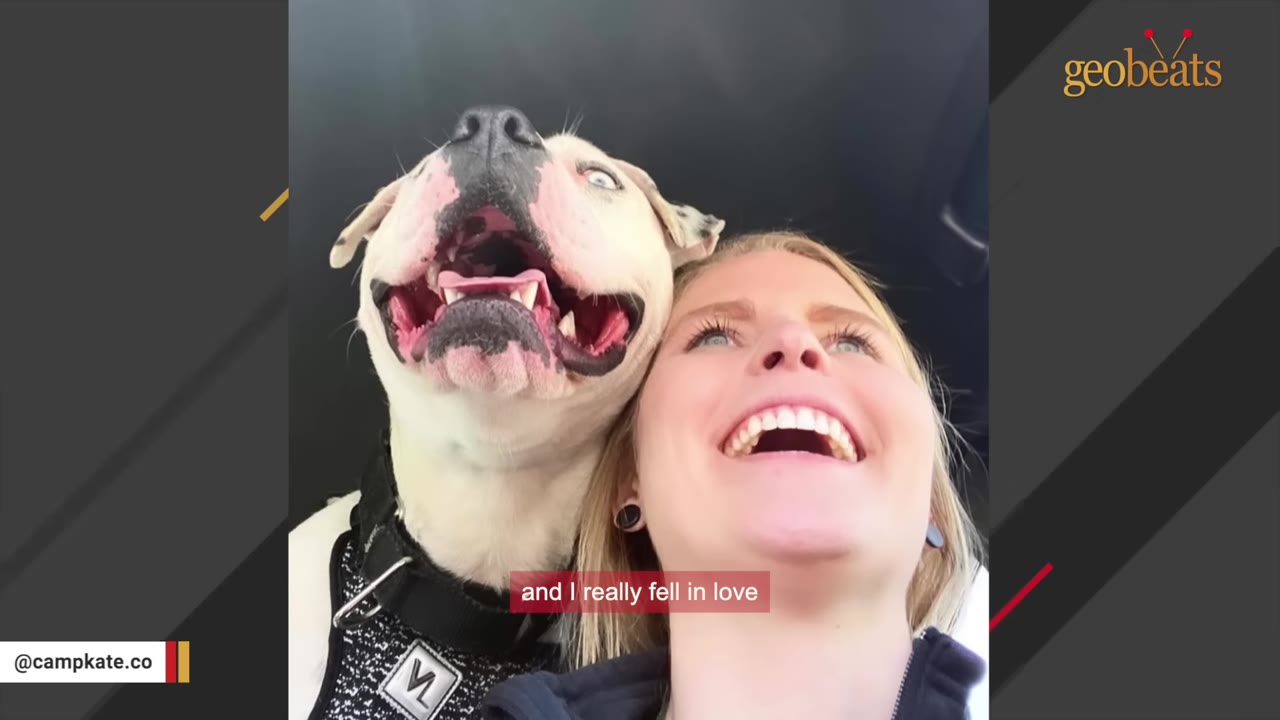 A close-up selfie of a smiling blonde woman next to a happy white dog with its mouth wide open, looking up joyfully.