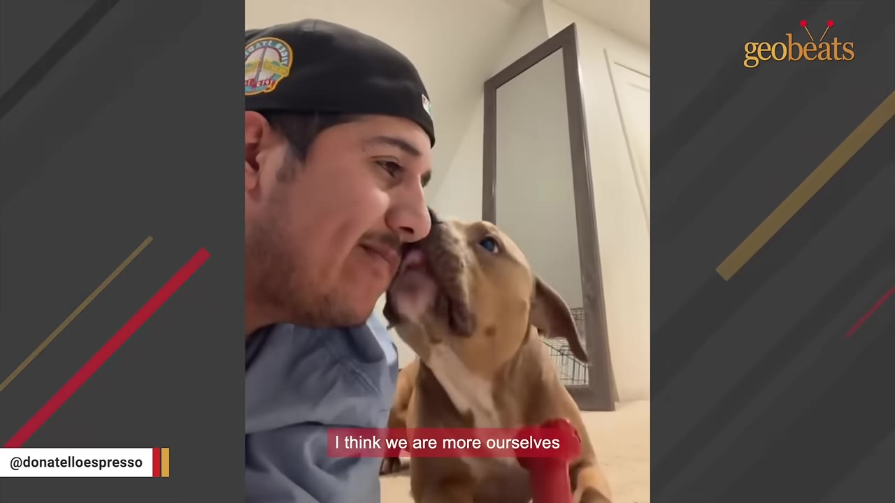 A close-up shot of a man wearing a black baseball cap smiling as a brown dog licks his cheek.