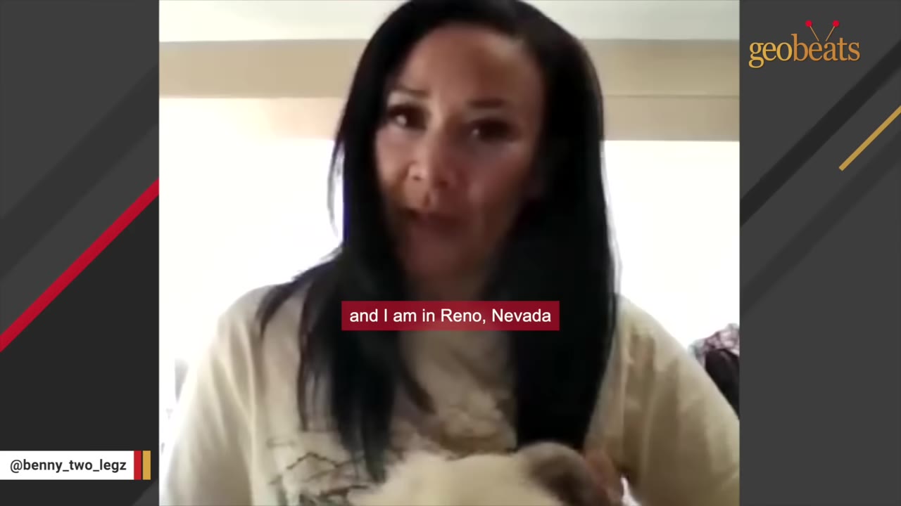 A woman with long dark hair speaks directly to the camera.