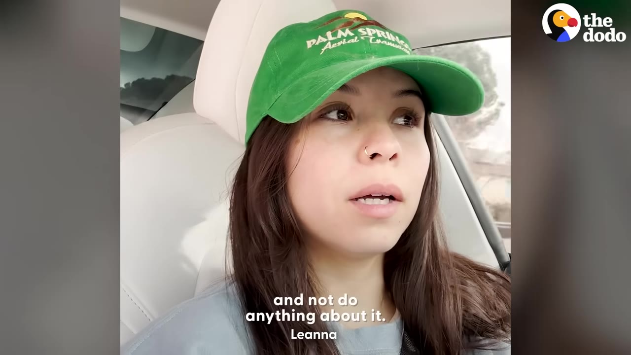 A close-up of a woman named Leanna wearing a green Palm Springs cap, sitting inside a car and looking concerned.
