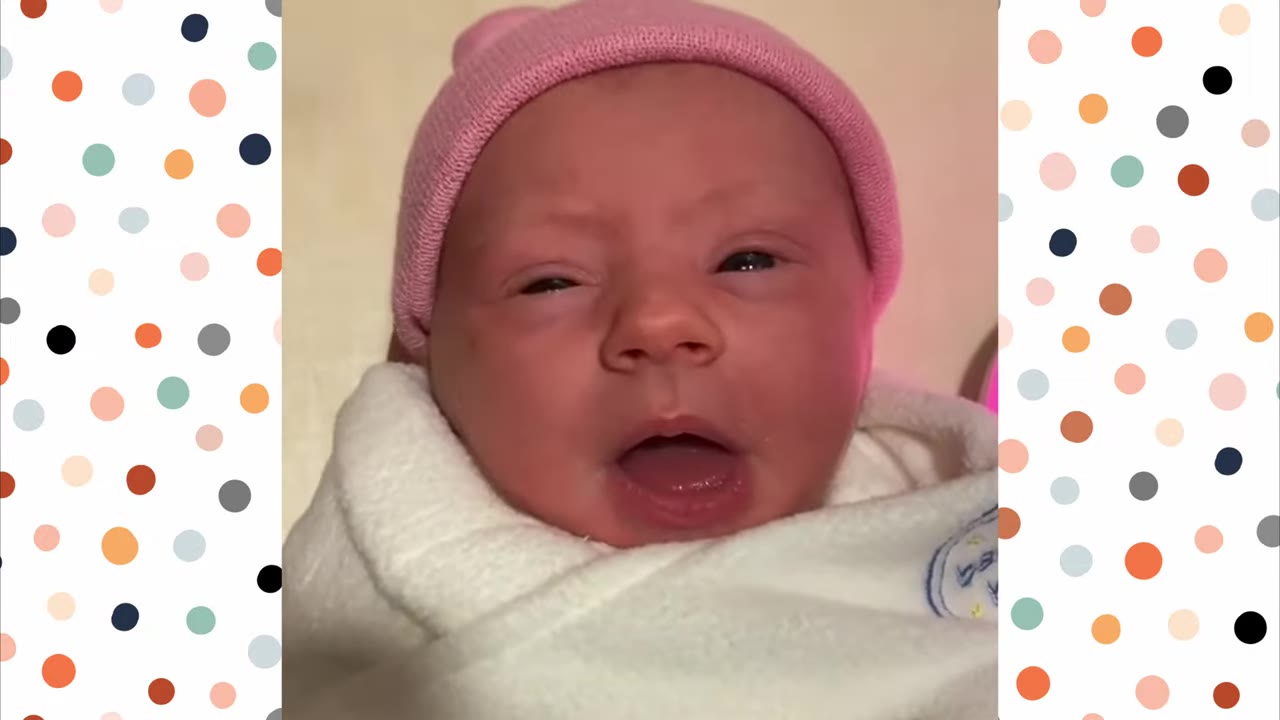 A close-up of a newborn baby wearing a pink knit hat and wrapped in a white swaddle blanket.