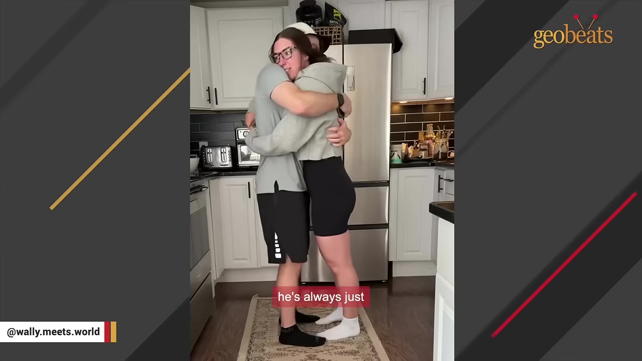A man and a woman hugging in a kitchen.