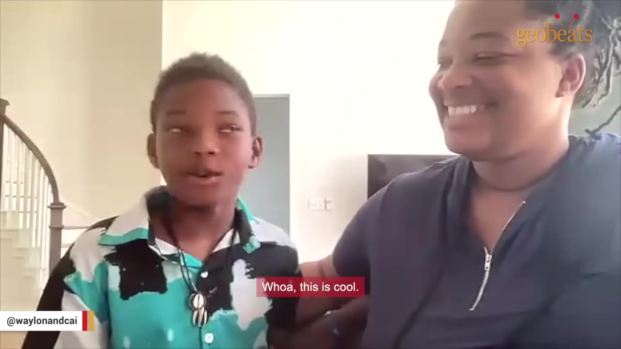 A young boy and a woman smiling inside a house, with a subtitle that reads 'Whoa, this is cool.'