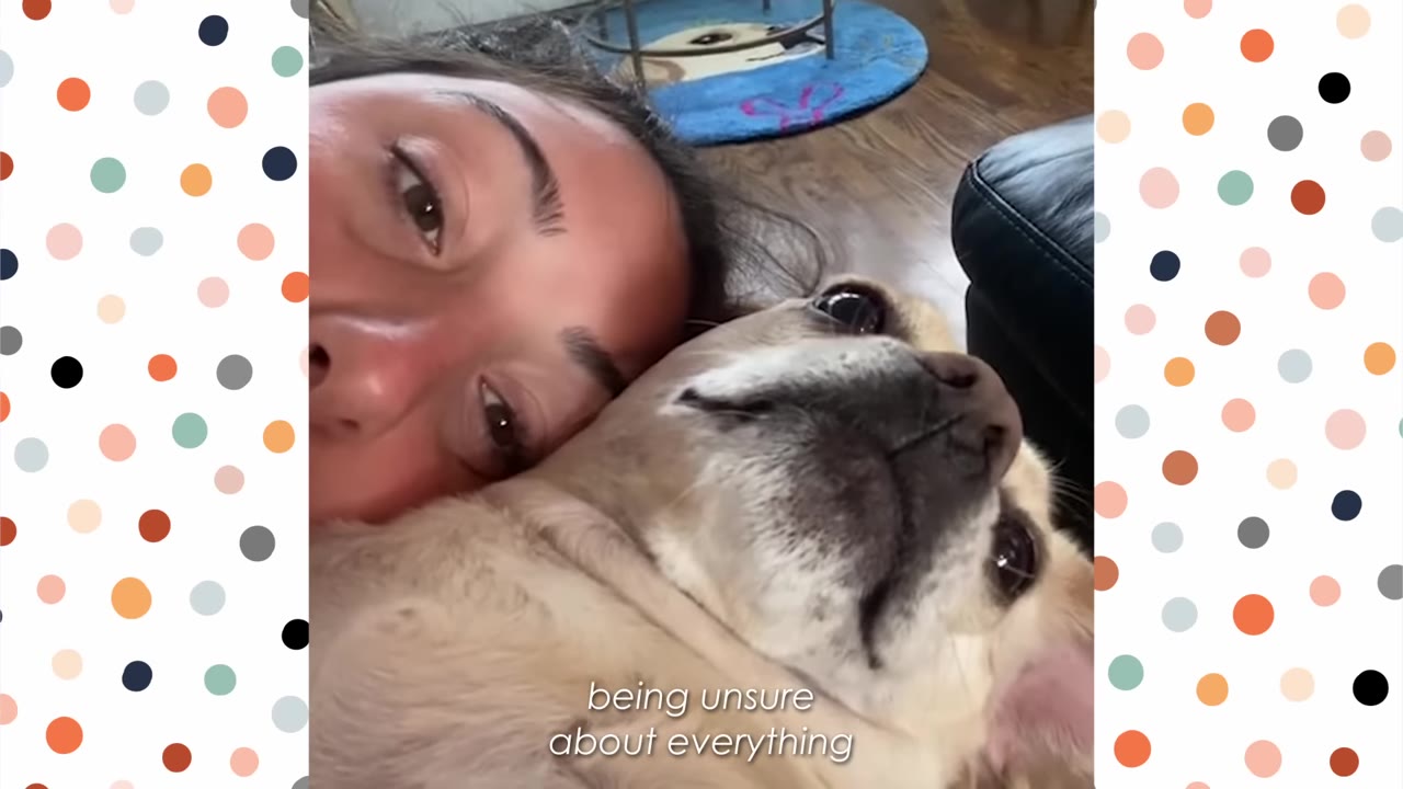 A close-up shot of a woman lying down with her head resting against a small light-colored dog, both looking towards the camera with gentle expressions.
