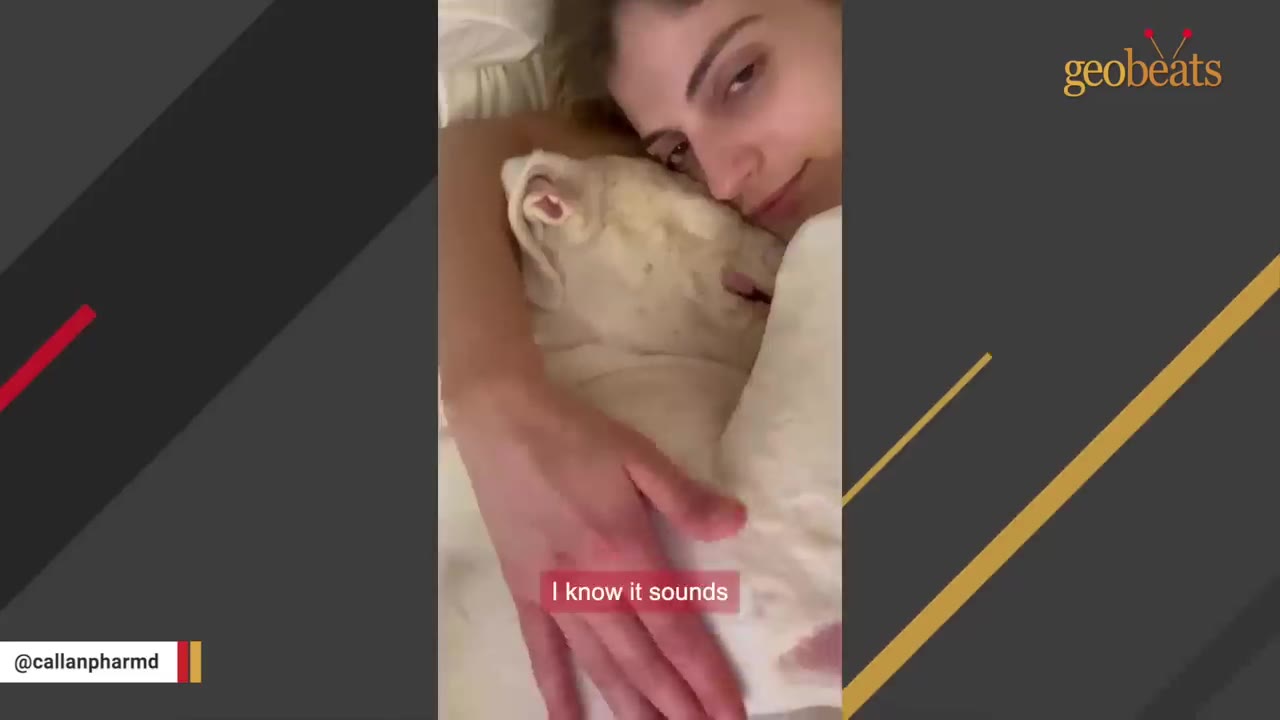A woman cuddling a white dog in bed, showing a close bond.