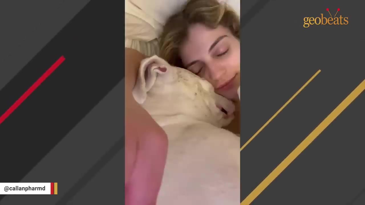 A close-up shot of a woman with her eyes closed, resting her face affectionately against her white dog as they cuddle together.