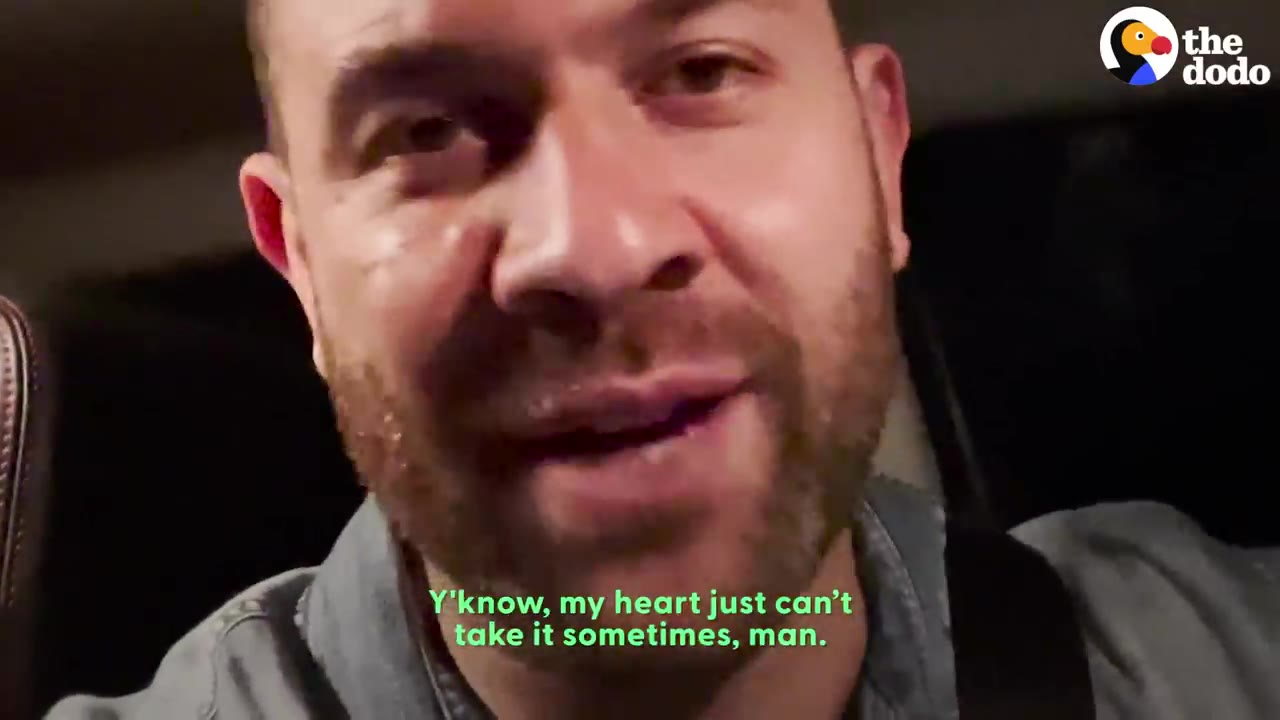 A close-up shot of a man speaking emotionally while sitting inside a car at night.