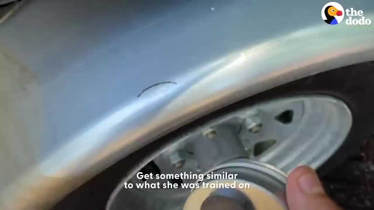A close-up of a hand placing a small metal canister onto the metal wheel well of a vehicle.