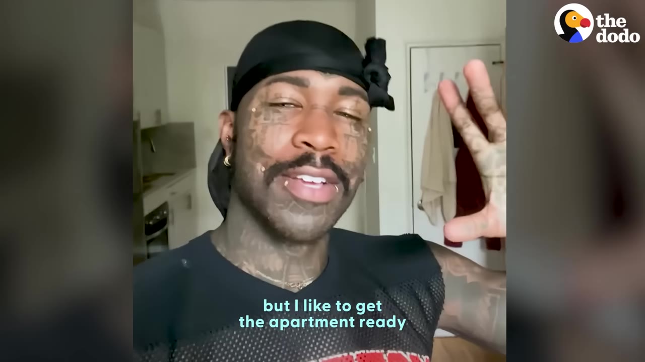 A man with facial tattoos wearing a black durag and top speaking directly to the camera.