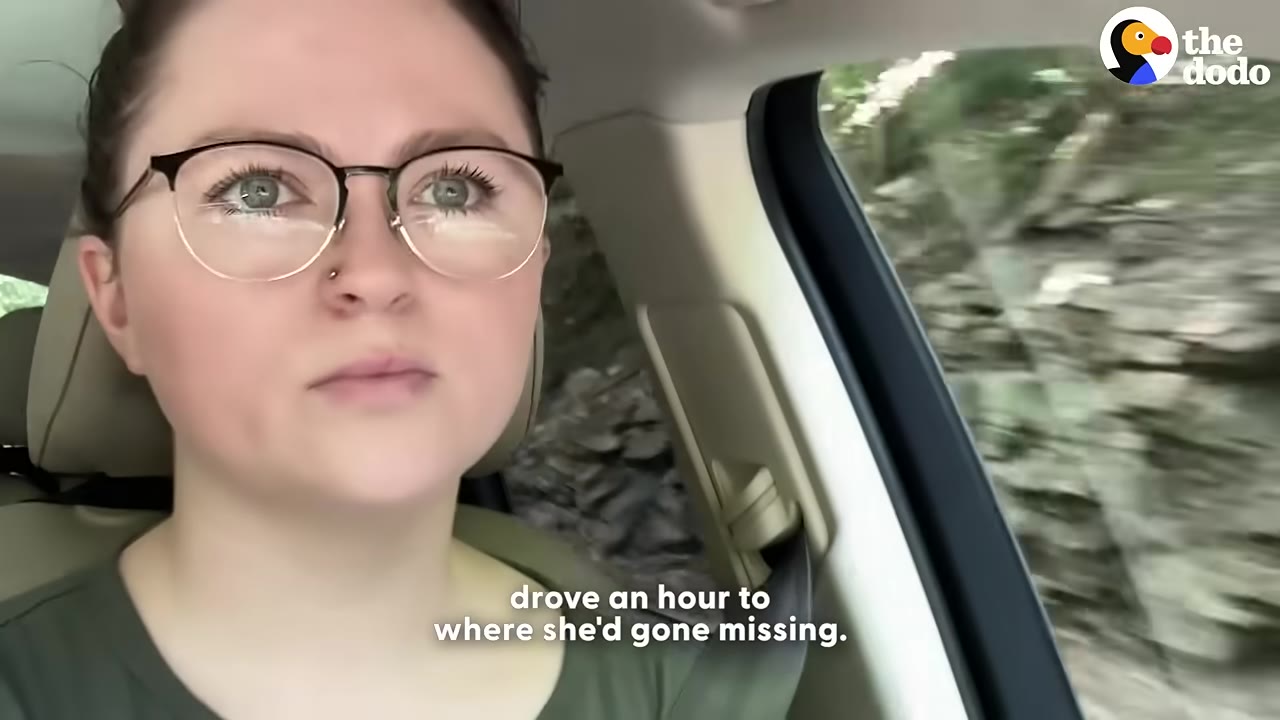 A close-up of a woman with glasses driving a car with a determined expression on her face.