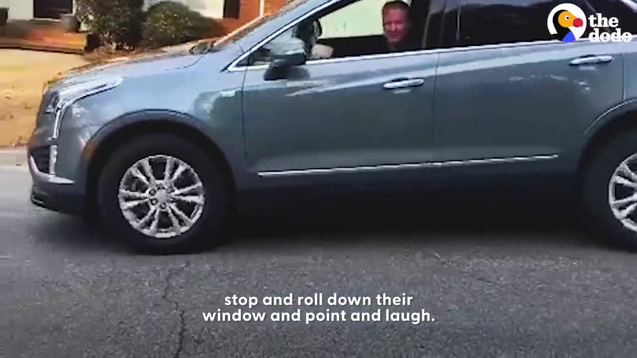 A driver in a grey SUV stopped on a neighborhood street with the window rolled down.