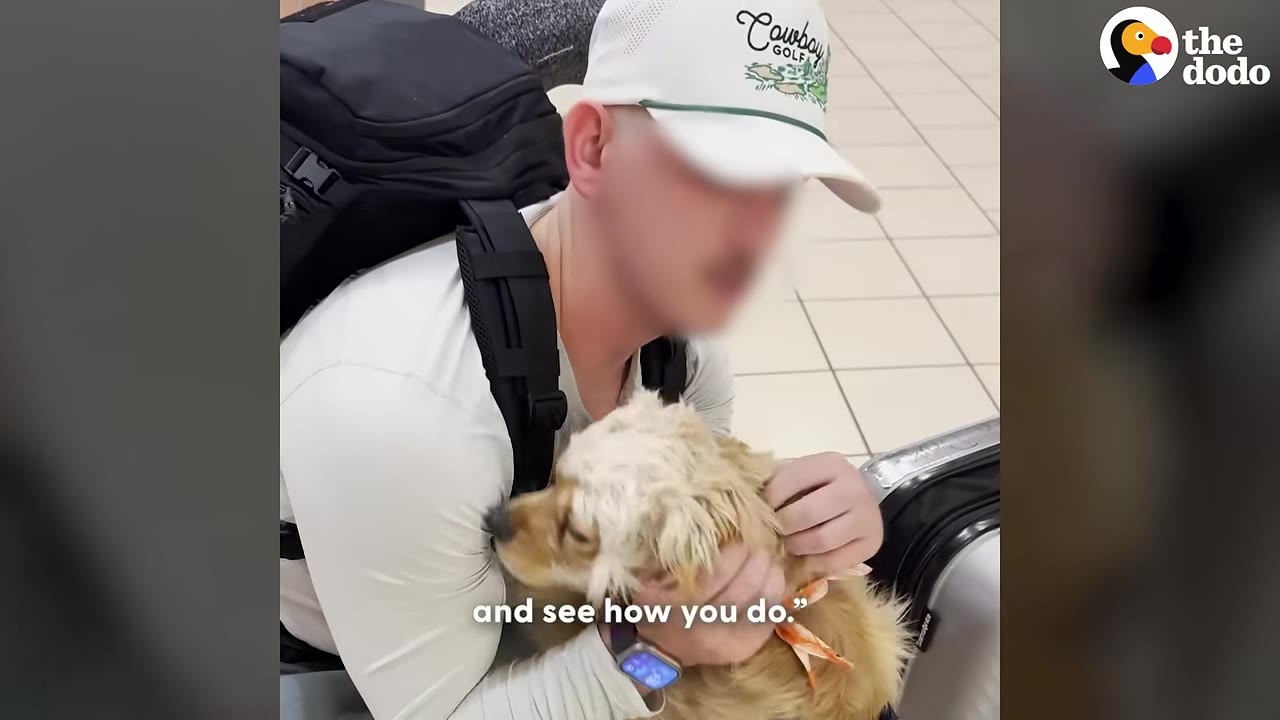 A man wearing a white cap and backpack holds a small, fluffy light-brown dog close to his chest.
